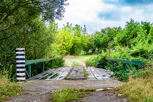Beautifully standing old wooden bridge over river in colored background close up, photography consisting of old wooden bridge above river in foliage, old wooden bridge at river for natural wild park
