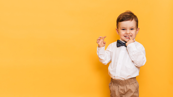 portrait of a cute little boy posing and laughing against a yellow background