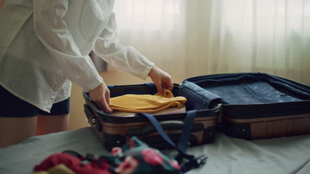 Female hands packing clothes into a suitcase