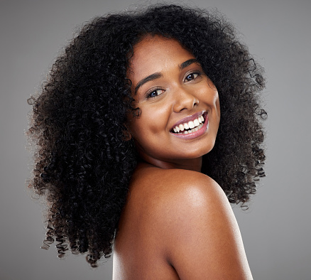 Black woman afro, beauty and smile for skincare, cosmetics or treatment against grey studio background. Portrait of happy isolated African American female smiling with teeth in care for perfect skin
