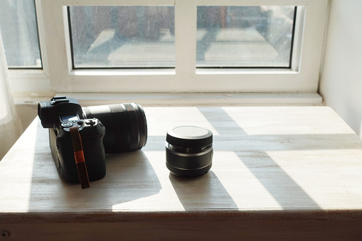 camera and lens on table in front of window