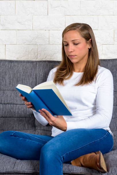 istock skeptical german blonde woman reading a book cross legged 1454125846