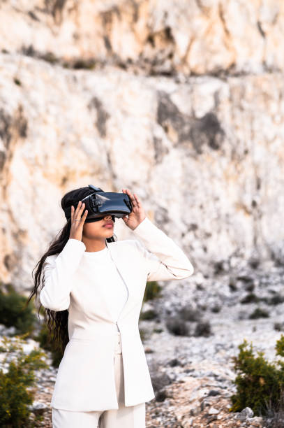 istock Elegant woman dressed in a white suit using a virtual reality goggles 1454126099