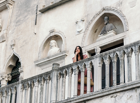 The Stylish young woman standing on the balcony of a beautiful old building in the city of Koper in Slovenia