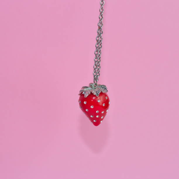 istock Red strawberry-shaped necklace on a pink background 1454126692