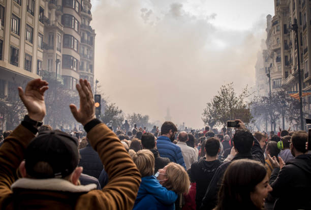 un homme applaudissant au milieu d’une foule de personnes qui regardent les fallas mascleta sur la place - manifestation photos et images de collection