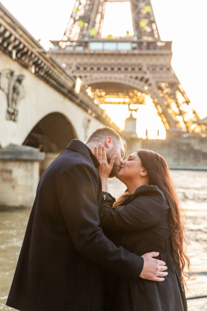 vertikale aufnahme des glücklichen paares beim fotografieren mit dem eiffelturm im hintergrund, paris, frankreich - paris france eiffel tower love kissing stock-fotos und bilder