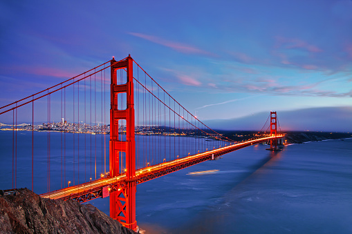 The Golden Gate Bridge at sunset in long exposure against a beautiful blue sky background