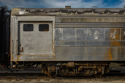 The old rusty gray train car in the park with the sky in the background