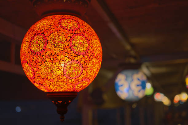 Glowing red traditional colorful Turkish lamp or handmade lantern, selective focus on lantern, blurred background, popular souvenir lanterns in cafe