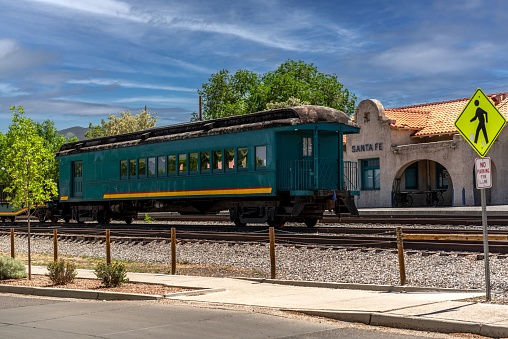 A green train cabin parked in front of the train station in Santa Fe and a road sign