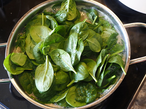 A close-up shot of spinach leaves in a boiling pot