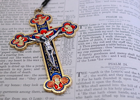 Detailed crucifix depicting the Holy Trinity laid on open Bible with Psalm 23