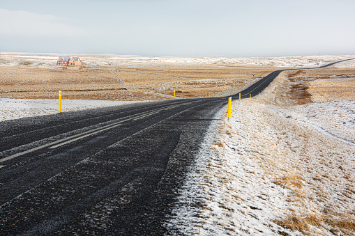 A chilling view of a paved country road between snow-covered fields in Iceland