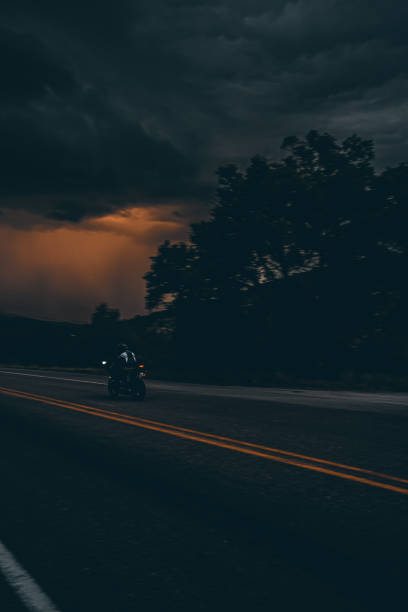 A man driving his motorcycle on a highway at dusk