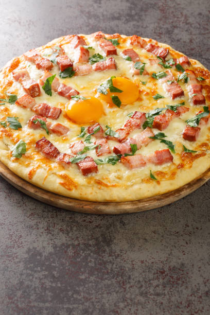 istock Hot pizza carbonara with bacon, egg, cheese and herbs close-up on a wooden board. Vertical 1454143204