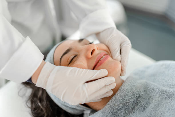 happy woman receiving a beauty treatment - massage creme imagens e fotografias de stock