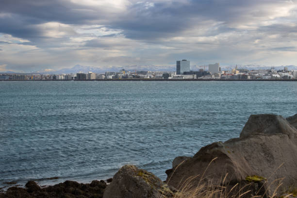 Coast of the North Atlantic ocean in the harbor. Cityview with an intense cloudy sky. Extremely windy day created waves. Port of Reykjavik, Iceland.