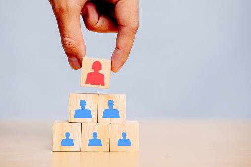 Holding a red wooden cube with a female CEO and human resources. Choosing a woman leader, business concept.