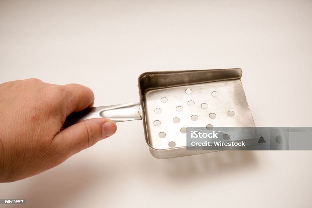 Hand holding a stainless tubular handled chip scoop on isolated white background A hand holding a stainless tubular handled chip scoop on isolated white background Color Image Stock Photo