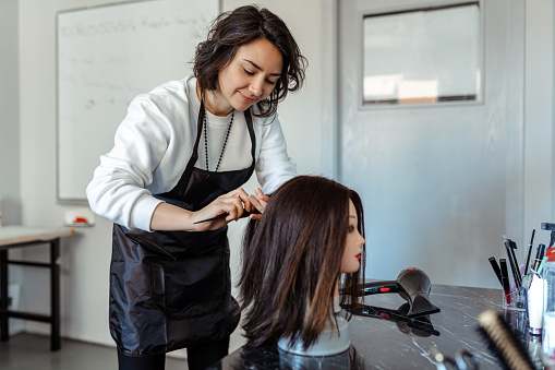 A Student working as a hairdresser with a dummy