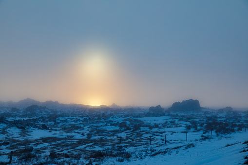 Male traveler visiting Kleifarvatn lake in Iceland with amazing snow covered mountain scenery during winter at sunset