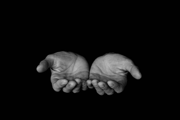 Close-Up Of Human Hand Praying Against Black Background