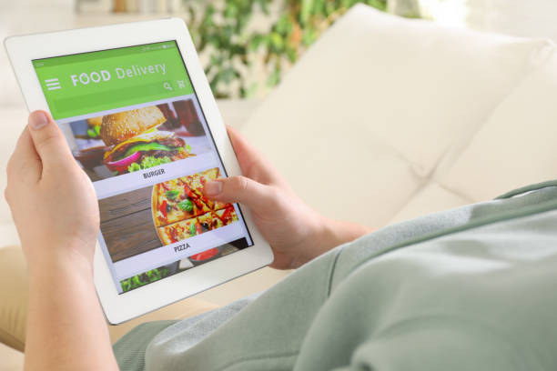 istock Man using tablet for ordering food online at home, closeup. Delivery service 1454154169