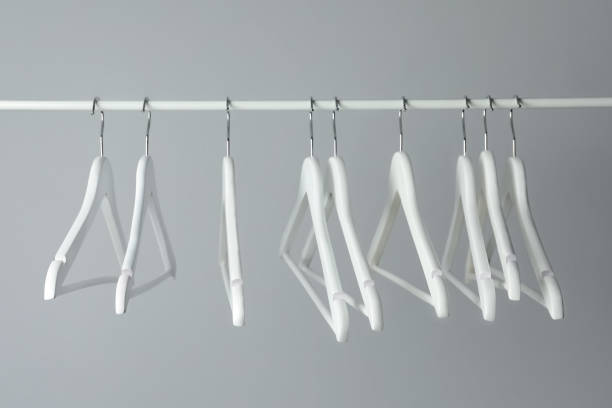 istock White clothes hangers on metal rail against light background 1454156238