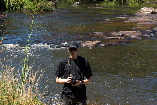 Young man on the riverbank with a camera in hand in brazil