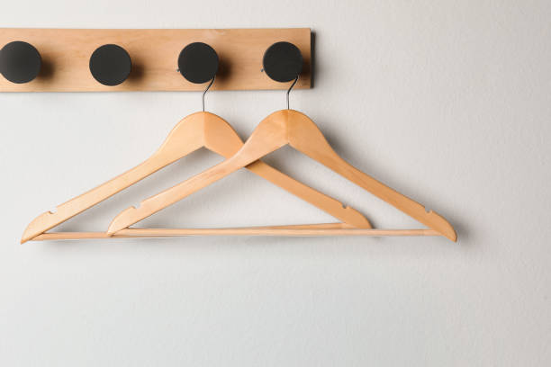istock Rack with empty wooden clothes hangers on white wall 1454157068