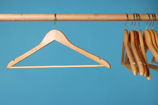 istock Empty clothes hangers on wooden rail against light blue background 1454157340