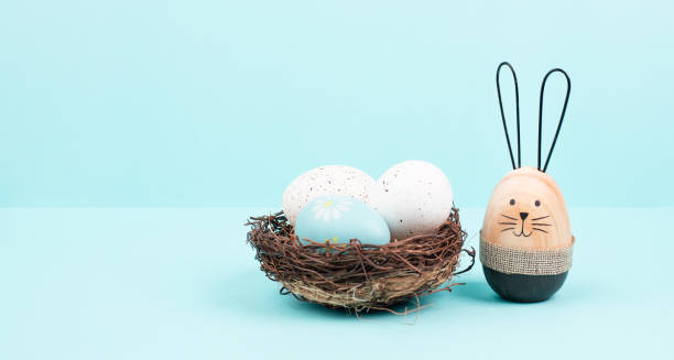 istock Easter bunny or rabbit sitting next to a wicker nest filled with colorful eggs, spring holiday 1454157479