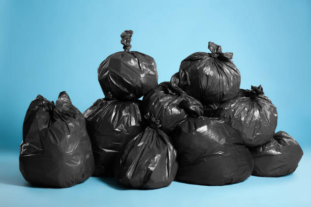 istock Black trash bags full of garbage on light blue background 1454158821