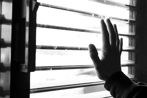 A hand touching the window during confinement, looking out of the window - quarantined due to Covid-19
