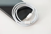 Black modern smartphone with accessory cable USB-C to Lightning cable that supports fast charging and is compatible with USB-C power adapters and computer ports