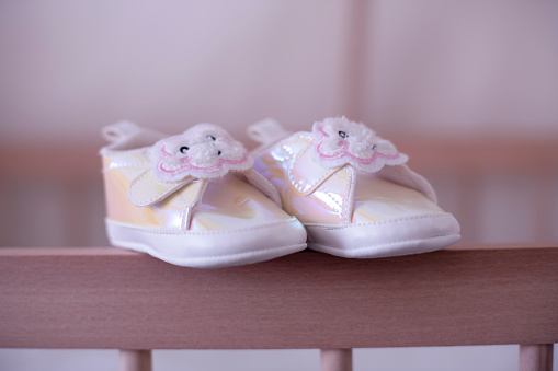 White baby shoes. Waiting baby, expecting new born, first steps, baby shower decoration concepts.