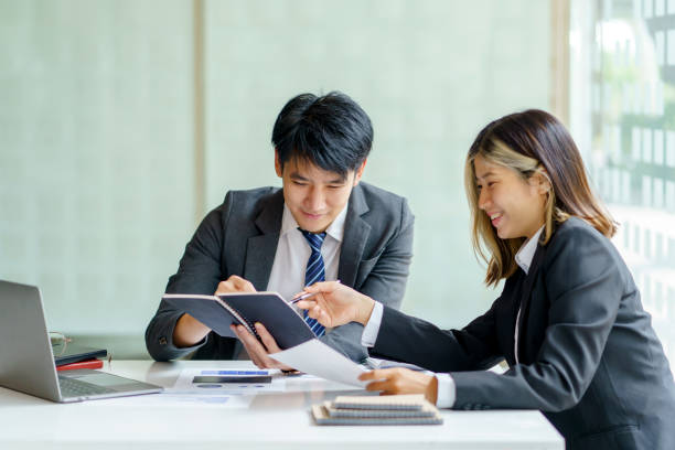 istock Two Asian business people discuss with new startup project Idea presentation, analyze planning at office. 1454164063