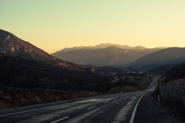 Panorama of mountains in light haze at sunset. Direct asphalted road among mountain ranges. New road in Turkey. Beautiful mountain landscape