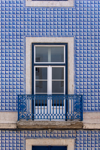 Traditional facade with balcony and covered with old azulejos in Lisbon, Portugal.