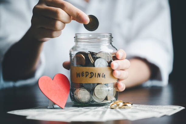 Save money for wedding and planning wedding concept. Sustainable financial goal for family life or married life. Miniature wedding on rows of rising coins, depicts savings or growth for new family. stock photo