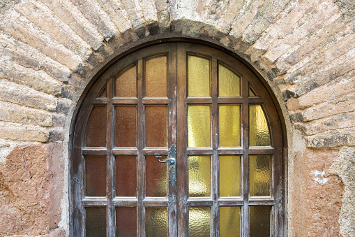 A closeup of old arch-shaped wooden doors and weathered stone wall