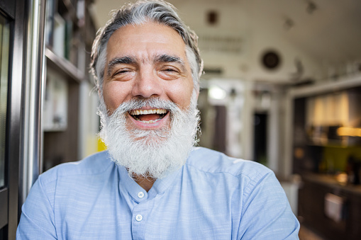 Cheerful senior man with a beard looking at camera. Contented emotion.