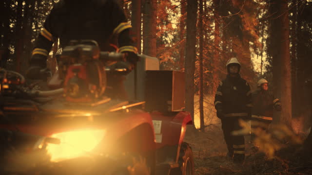 Cinematic Shot of a Squad of Firefighters with Special Equipment Encircle a Raging Forest Fire Before the Blaze Gets Out of Hand. Fireman on an All-Terrain Vehicle Moving Along with the Team.