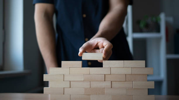 istock Man hand building wall with wooden blocks 1454175959