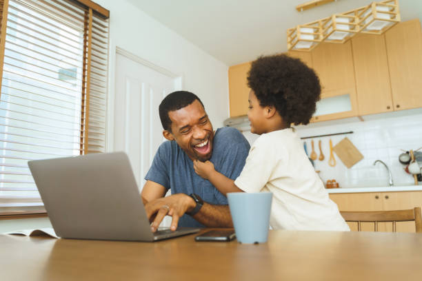 istock African American father working from home on laptop while his Cheerful son distracts 1454177435