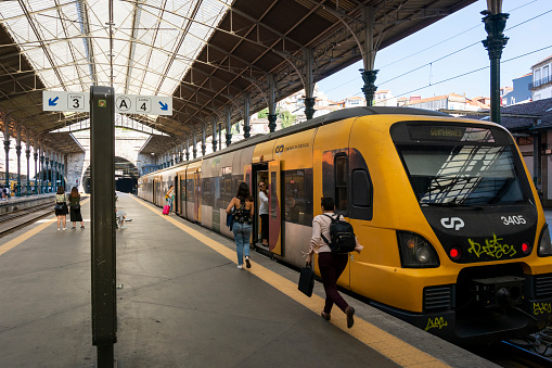 Porto, Portugal – August 08, 2019: Woman running to catch the yellow train. Sao Bento station, Porto, Portugal