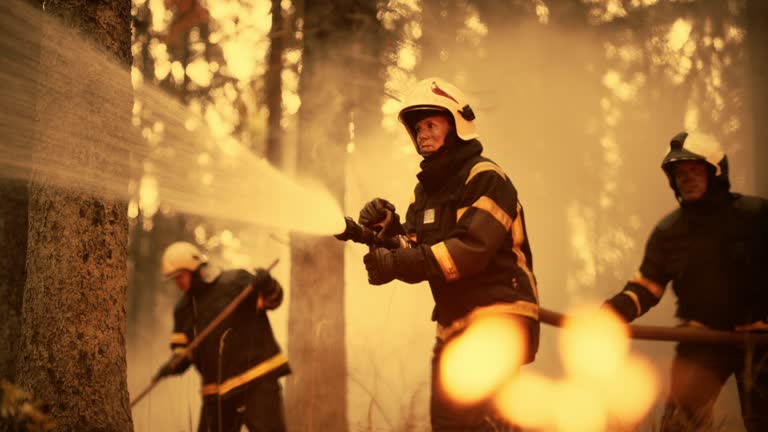 Portrait of a Brave Professional Female Firefighter Using a Firehose to Fight a Raging Dangerous Wildfire. Experienced Team Skillfully Manage the High-Pressure Water and Stay Protected and Safe.