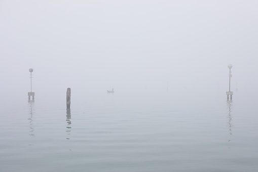 Lagoon landscape in Venice - Italy. In the distance we see a Venetian shrouded in fog  on his rowboat.