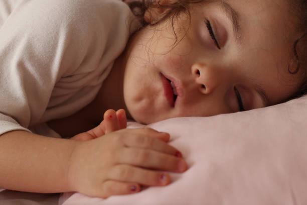 istock Little girl sleeping in her bed 1454180082